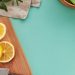 A bright flat lay of citrus fruits, vegetables, and spices on a teal background, perfect for culinary themes.